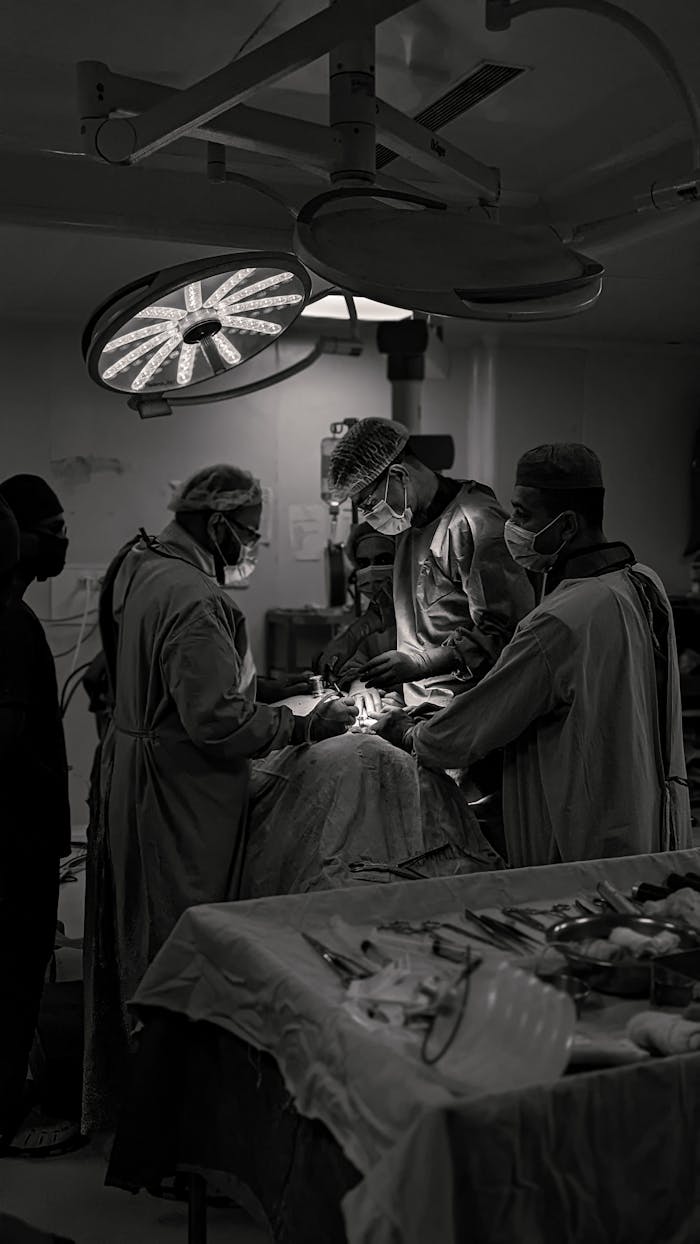 gallery-4 Team of surgeons in an operating room conducting surgery in black and white.