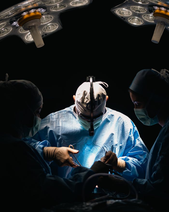 gallery-6 Surgeons focused in an operating room performing lifesaving surgery under bright surgical lights.